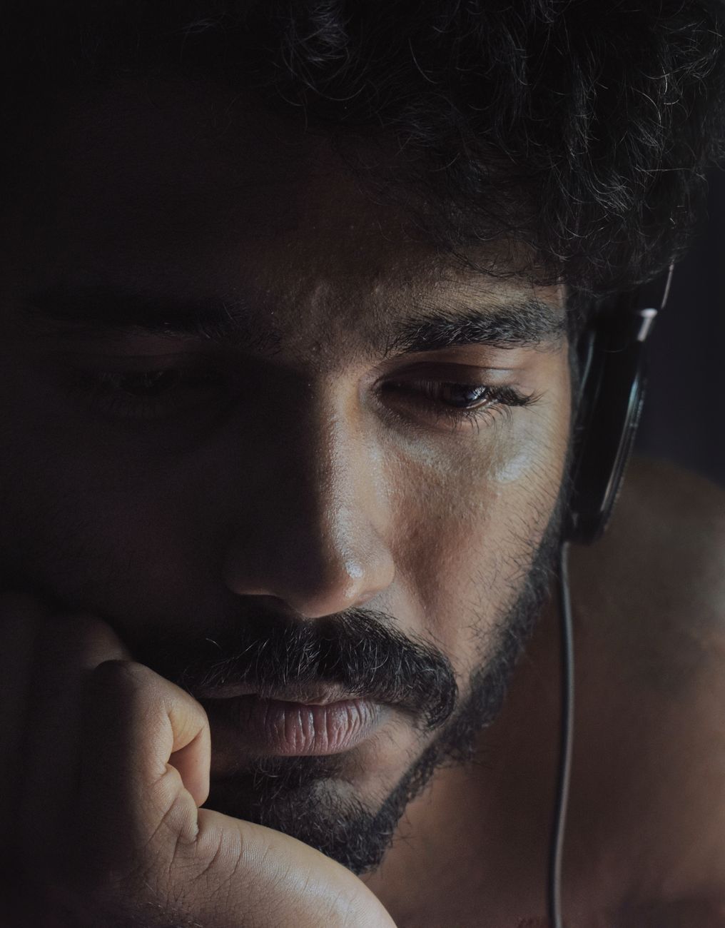 close up photo of man looking sad while wearing black headphones